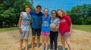 Campers will volleyball on sand volleyball court